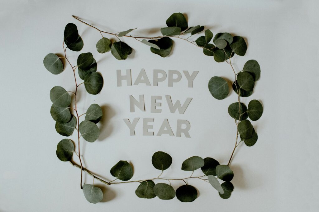 A picture of the words Happy New Year laid out on a table with a green-leafed garland around them.