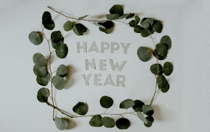 A picture of the words Happy New Year laid out on a table with a green-leafed garland around them.