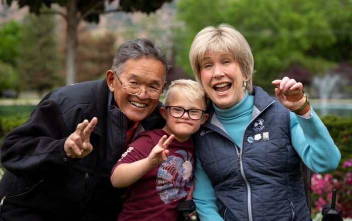 A picture of Joni, Ken, and a little boy with down syndrome all smiling at the camera.