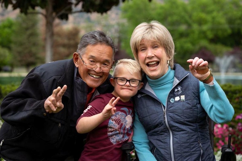 A picture of Joni, Ken, and a little boy with down syndrome all smiling at the camera.