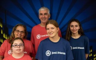 A group photo of Brian, Cheryl, Sophia and their other two daughters all smiling at the camera in their Joni and Friends t-shirts.
