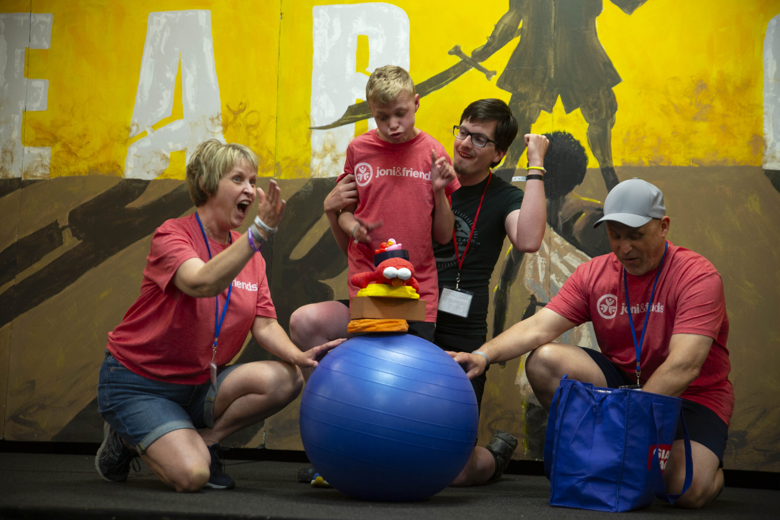 A picture of Cole playing with three Joni and Friends buddies with a large blue exercise ball and what appears to be a puppet.