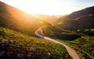 A picture of a windy road through bright green hills.