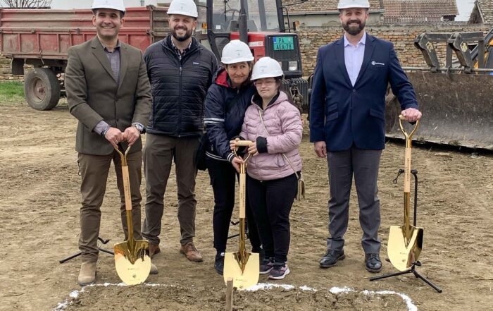 A group photo of Jason Holden with our Joni and Friends Serbia partners as well as a young girl who has Down Syndrome. All are smiling at the camera with shovels in their hands and hard hats.