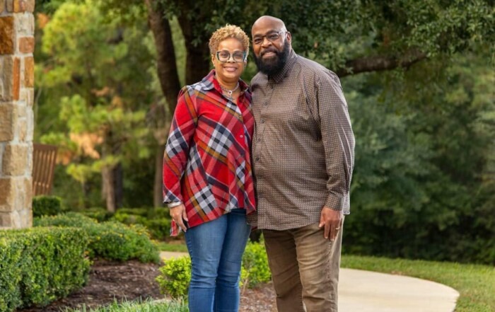 A picture of Cedric and his wife side-hugging and smiling at the camera.