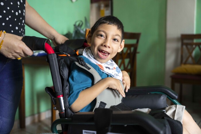 A close-up picture of Fernando seated in his new wheelchair and smiling at the camera.