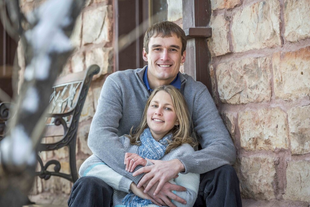 Caleb sitting and gently embracing Rachel, both smiling and posing happily for the camera.