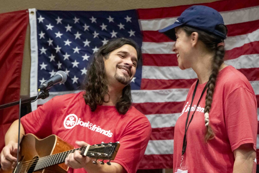 David is playing his guitar and singing while gazing lovingly at his wife, Deborah.