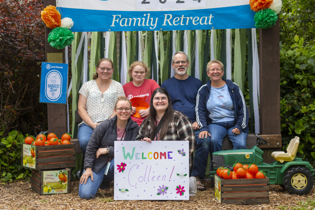 The Shipman family posing for a picture with a Joni and Friends 2024 Family Retreat banner in the background.