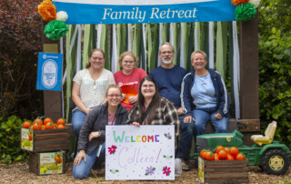 Shipman family posing for a picture with a Joni and Friends 2024 Family Retreat banner in the background.