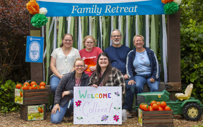 Shipman family posing for a picture with a Joni and Friends 2024 Family Retreat banner in the background.