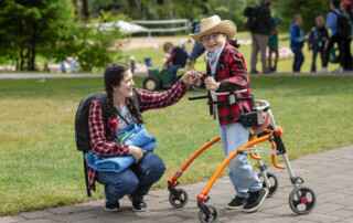 Anna assisting Sophia as she walks with her walker, both smiling and excited, at Family Retreat.