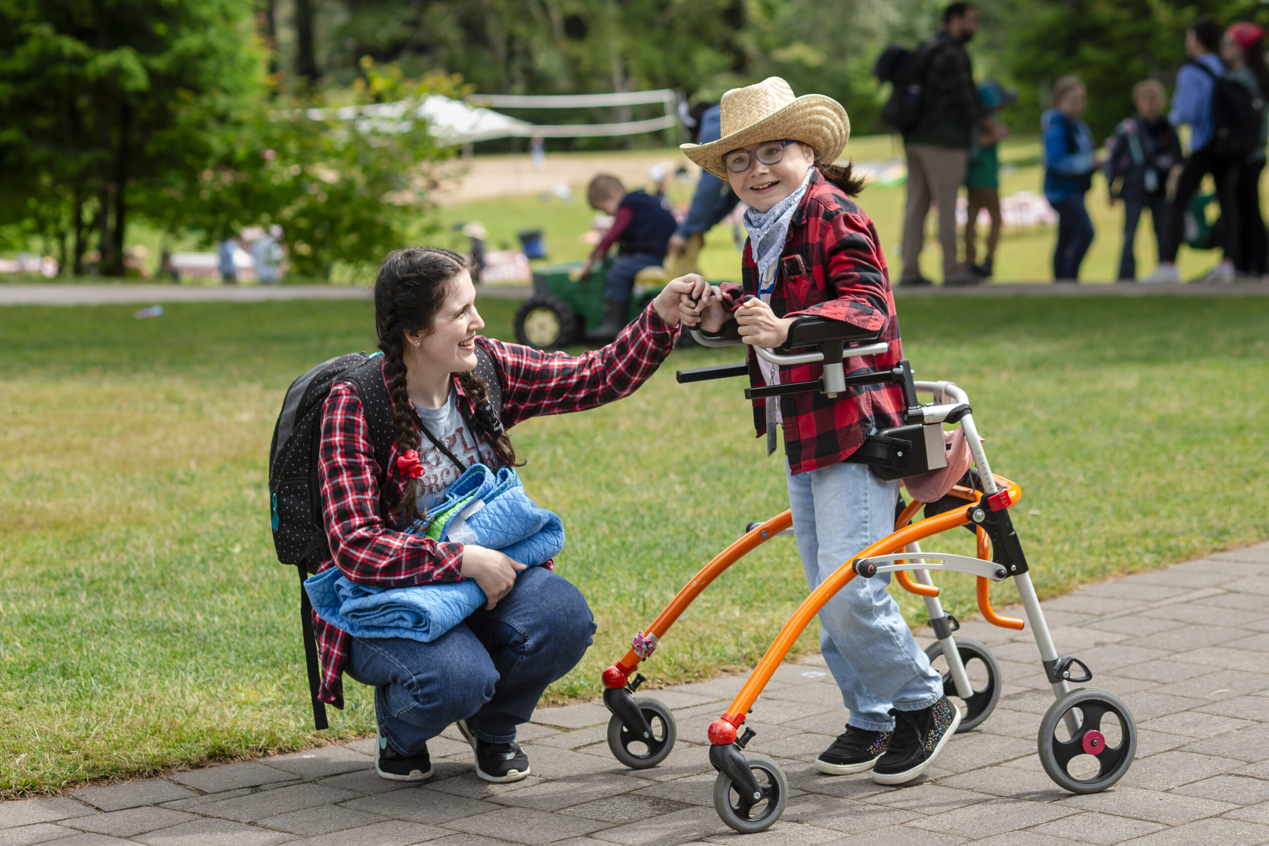 Anna assisting Sophia as she walks with her walker, both smiling and excited, at Family Retreat.