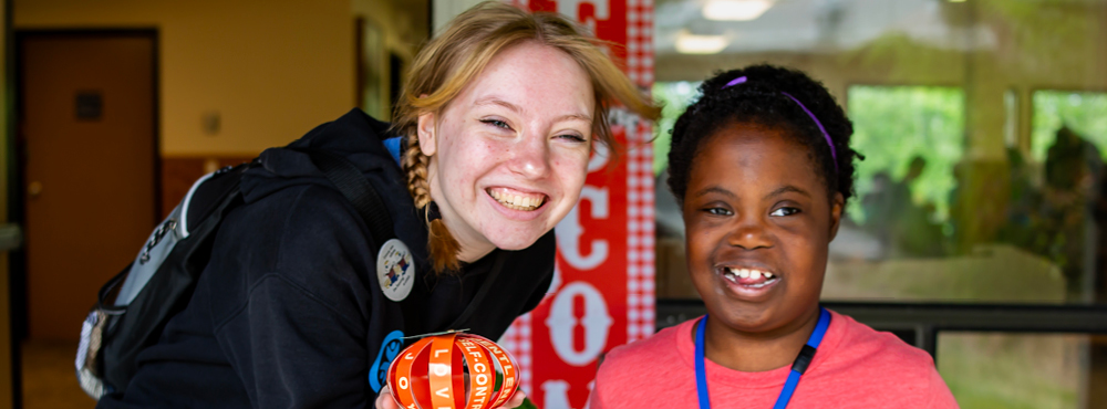 A smiling volunteer and camper are having a blast at Family Retreat!