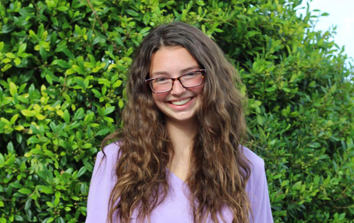 Heidi Swartley smiling at the camera with tall green plants in the background.