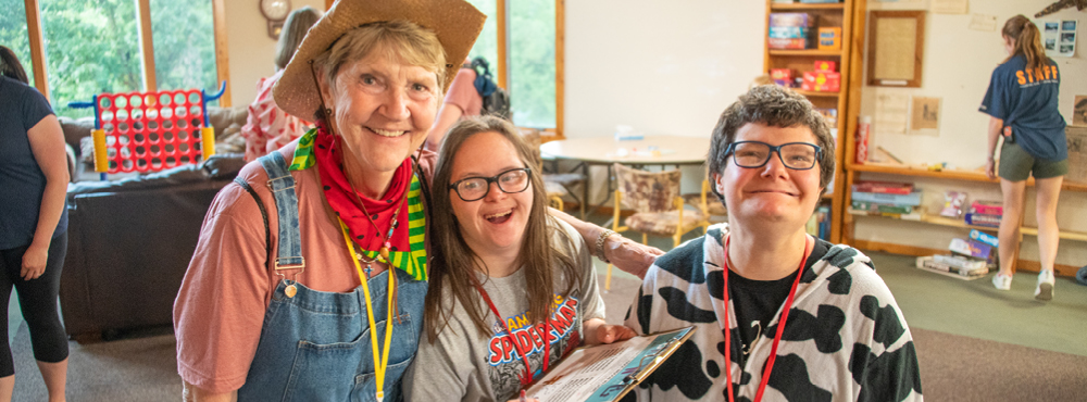 Three people standing together, all smiling broadly and looking joyfully at the camera.