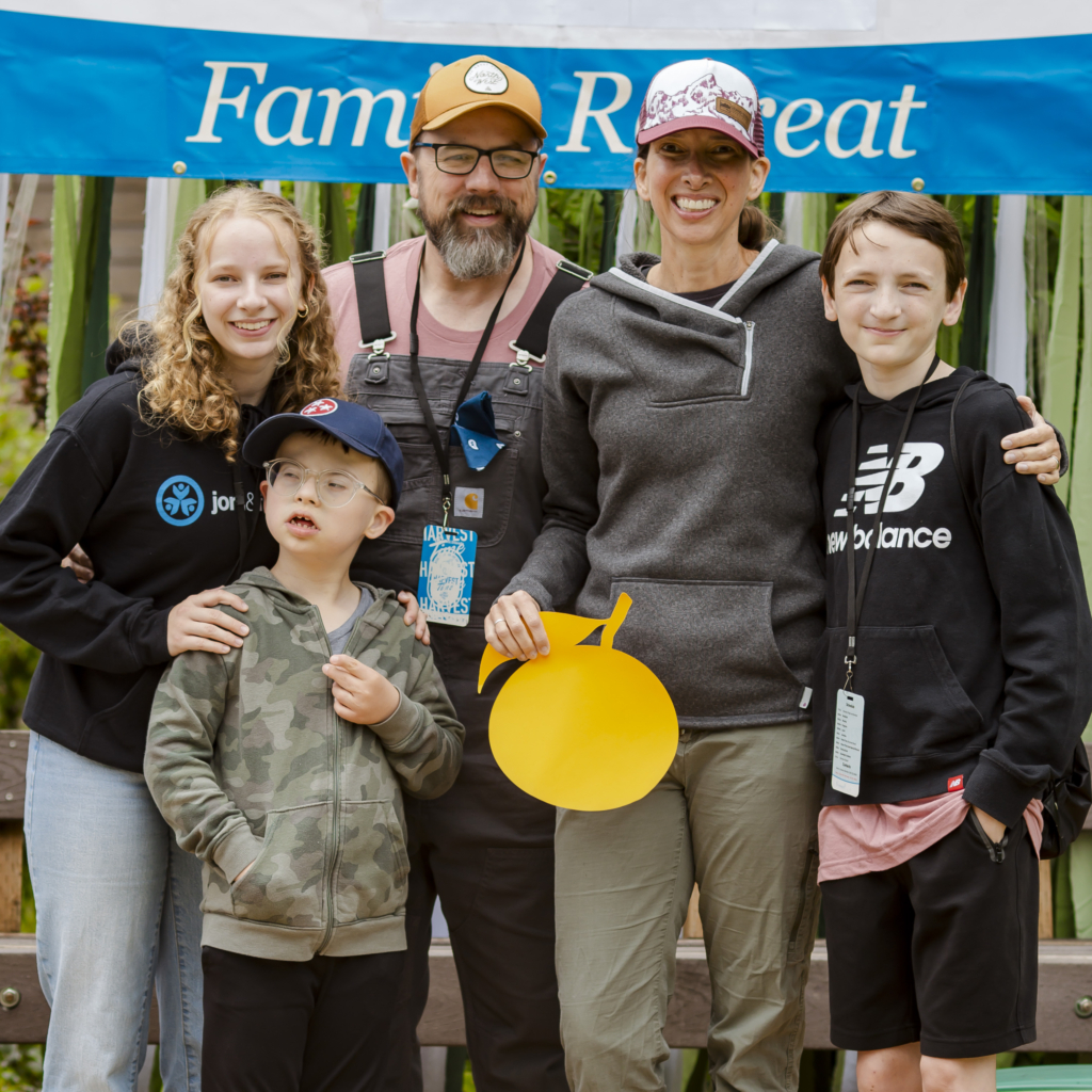 A family picture of Colton with his sister on the left, holding his shoulder, his father behind him, and his mother and brother on the right, all happily posing for the camera.