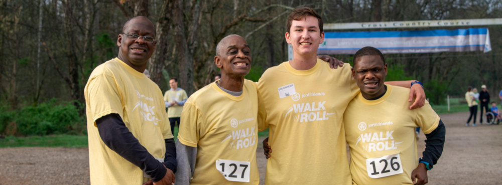 A group of men pose for a photo in yellow shirts at a Walk 'N' Roll event