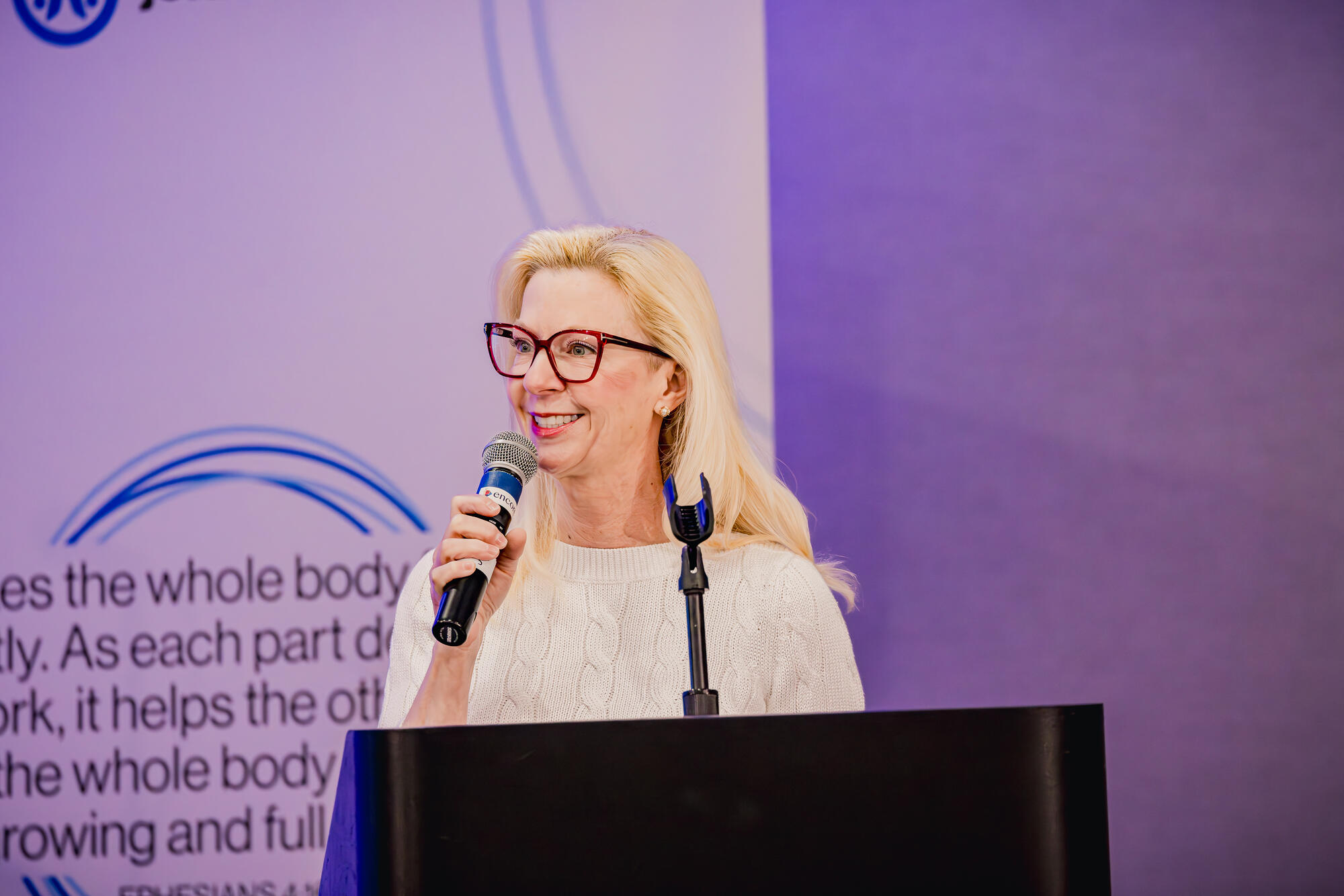 Laura Gardner public speaking with a microphone.