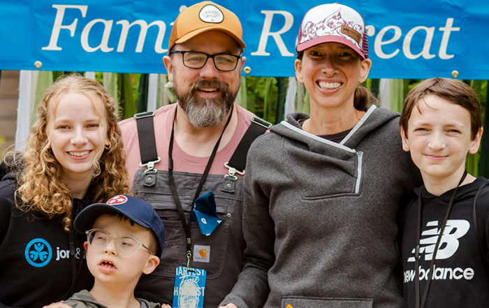 A family picture of Colton with his sister on the left, holding his shoulder, his father behind him, and his mother and brother on the right, all happily posing for the camera.