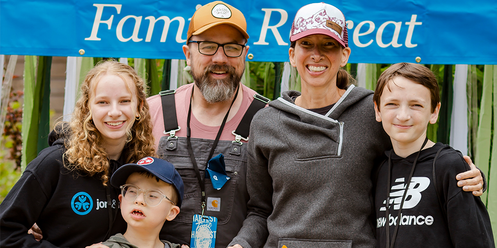 A family picture of Colton with his sister on the left, holding his shoulder, his father behind him, and his mother and brother on the right, all happily posing for the camera.