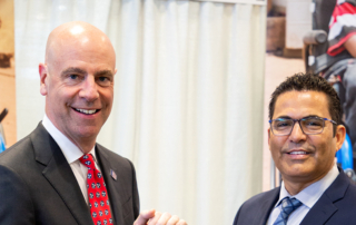 Damon T. Hininger, President and CEO of CoreCivic, and Paul Dorthalina, Director of Wheels for the World at Joni and Friends, are smiling and posing for the camera while holding an award together.