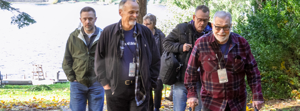 A group of people walking outdoors by a lake at a Joni and Friends event