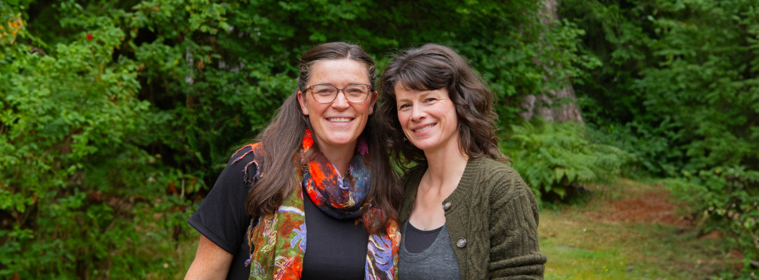 Women pose for a photo surrounded by greenery