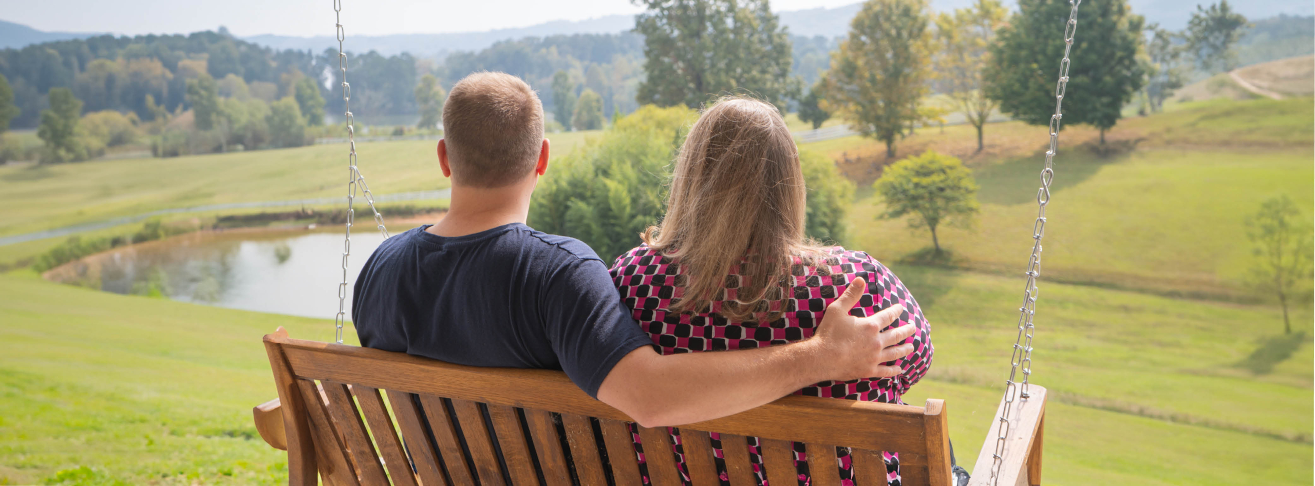 A couple sits on a porch swing relaxing and admiring the scenery while experiencing respite at Marriage Getaway.