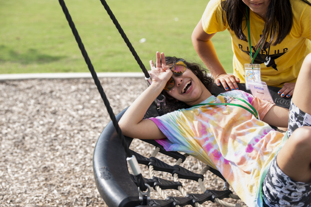 Natalia lying on a swing, having so much fun, while her sister Amelia pushes her.