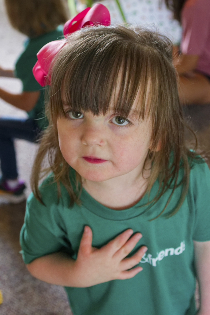 Natalie is looking intently at the camera, wearing a cute ribbon in her hair and a green t-shirt featuring the Joni & Friends logo.