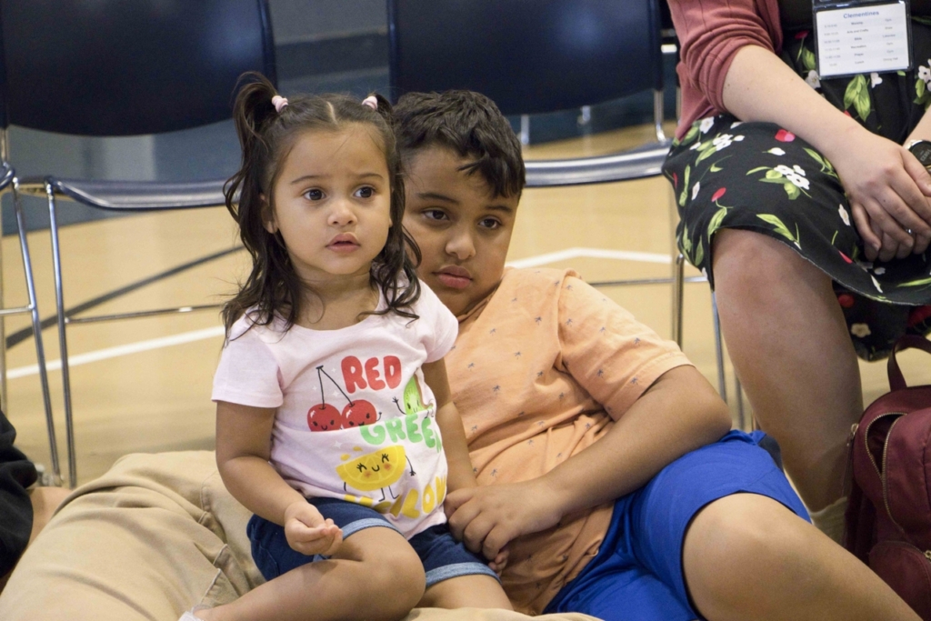 Carin and Oscar are sitting next to each other, both looking intently focused on something in front of them.