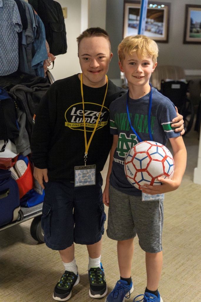 Josiah and Joshua standing next to each other, posing for the camera. Joshua is holding a soccer ball.