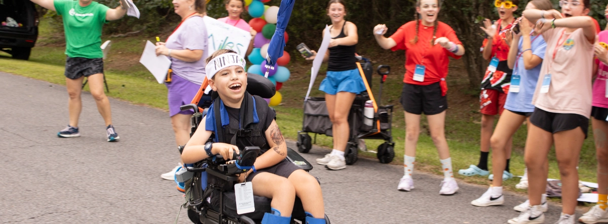 A camper being cheered on by volunteers and other campers