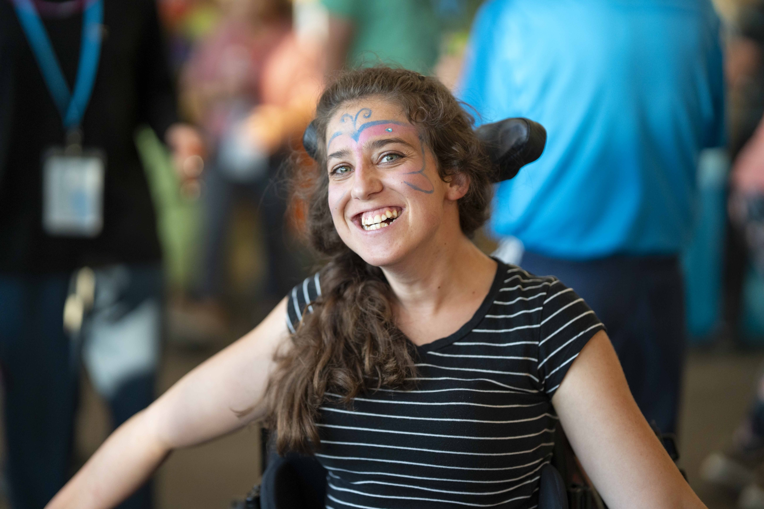 Jaycee smiles broadly during Family Retreat, with colorful butterfly face paint on her face.