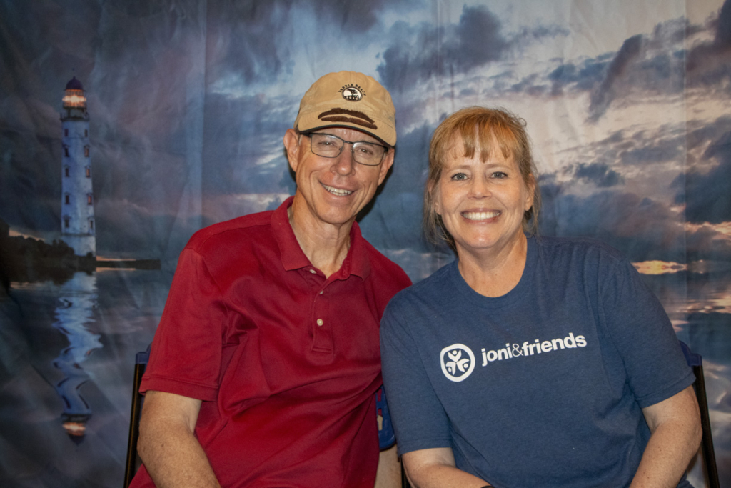 Pal and Julie sitting next to each other, smiling warmly and posing for the camera. They are dressed casually, radiating happiness and togetherness.