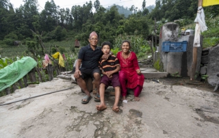 Surya sitting between her mom and dad, all of them smiling and looking joyful and happy, sharing a moment of warmth and togetherness.