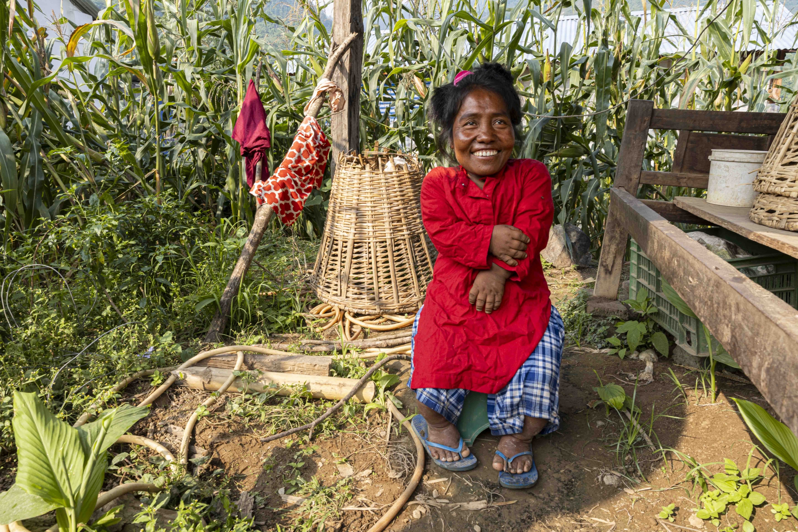 Kalyani standing with a big smile, with corn plants in the background.