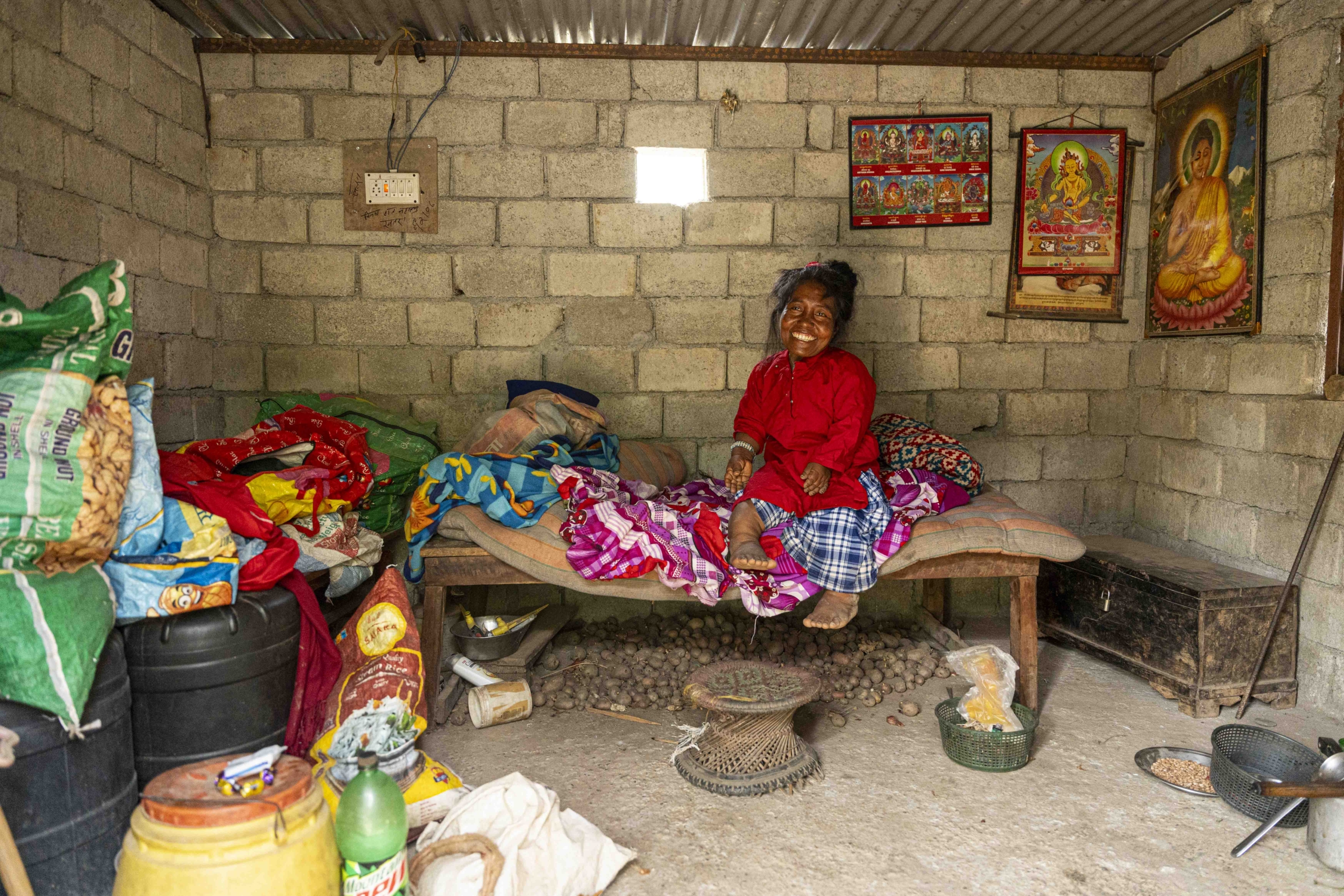 Kalyani with a huge smile, sitting on her bed inside her home.