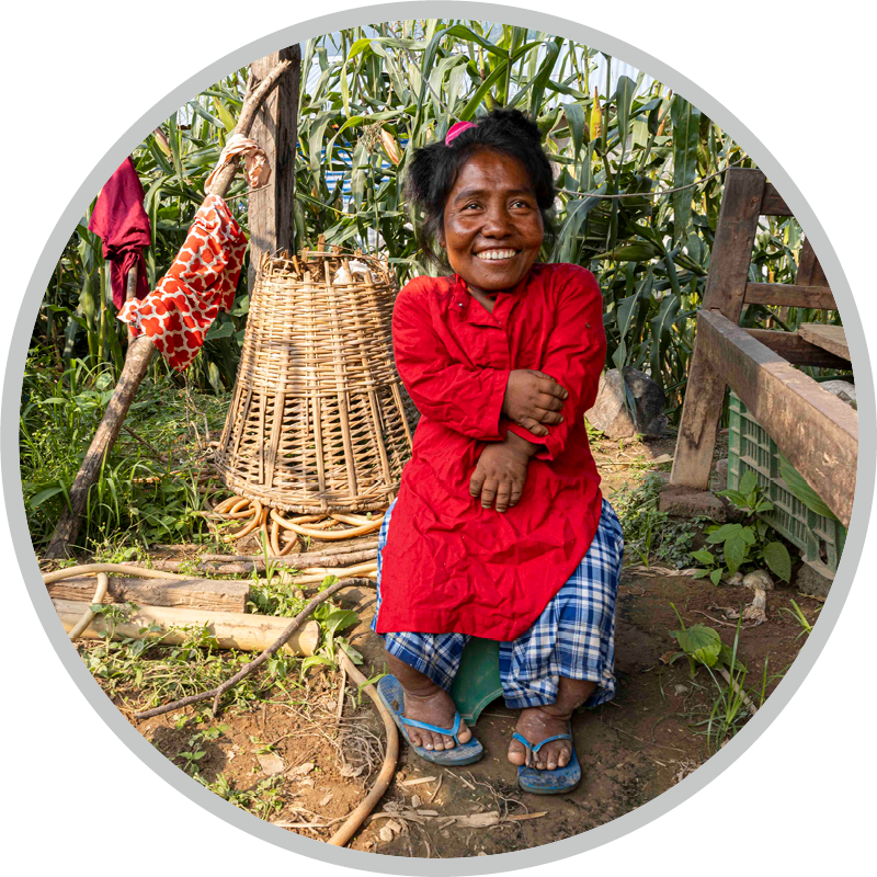 Kalyani standing with a big smile, with corn plants in the background.