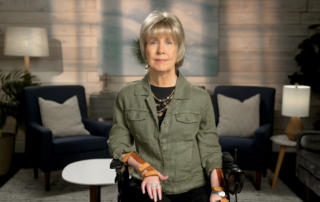 Joni Eareckson Tada is looking at the camera with a backdrop of a living room setup.