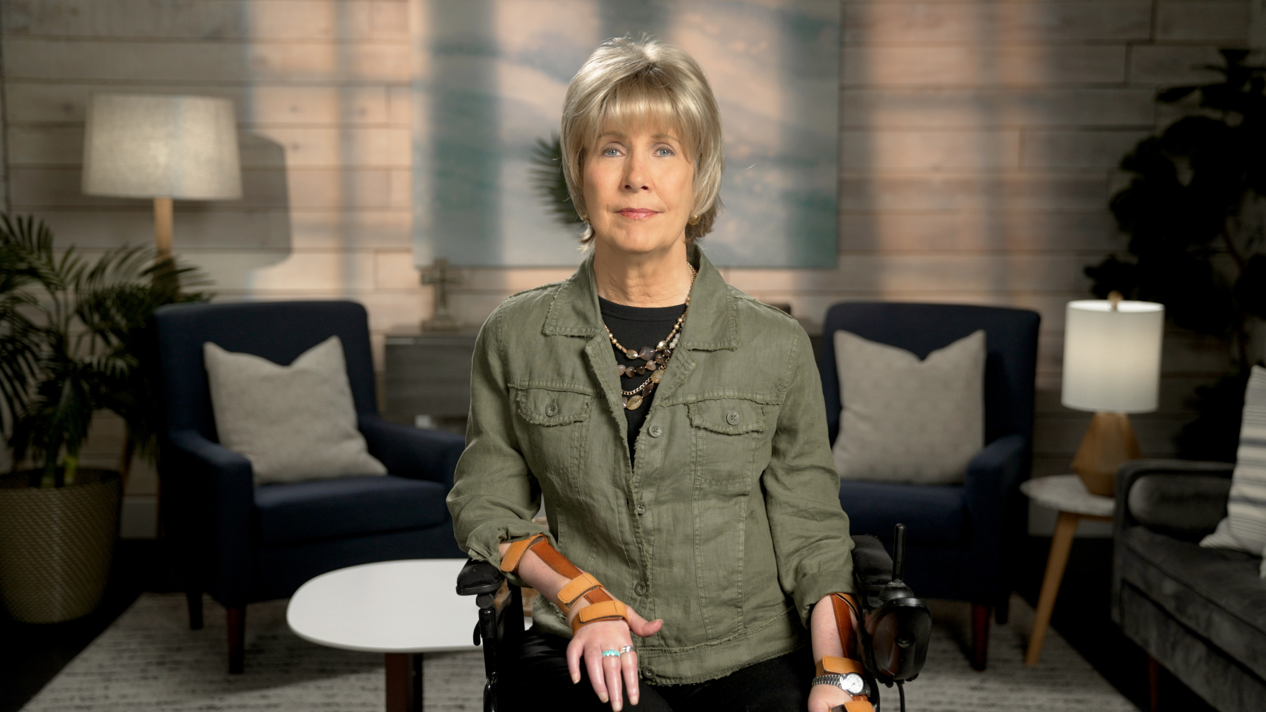 Joni Eareckson Tada is looking at the camera with a backdrop of a living room setup.