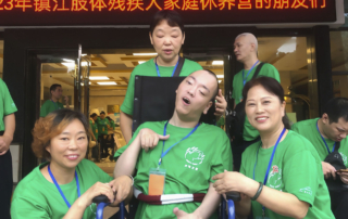 Lu Tong in his new wheelchair, a gift from Joni and Friends, smiling with the three volunteer women at the International Family Retreat.