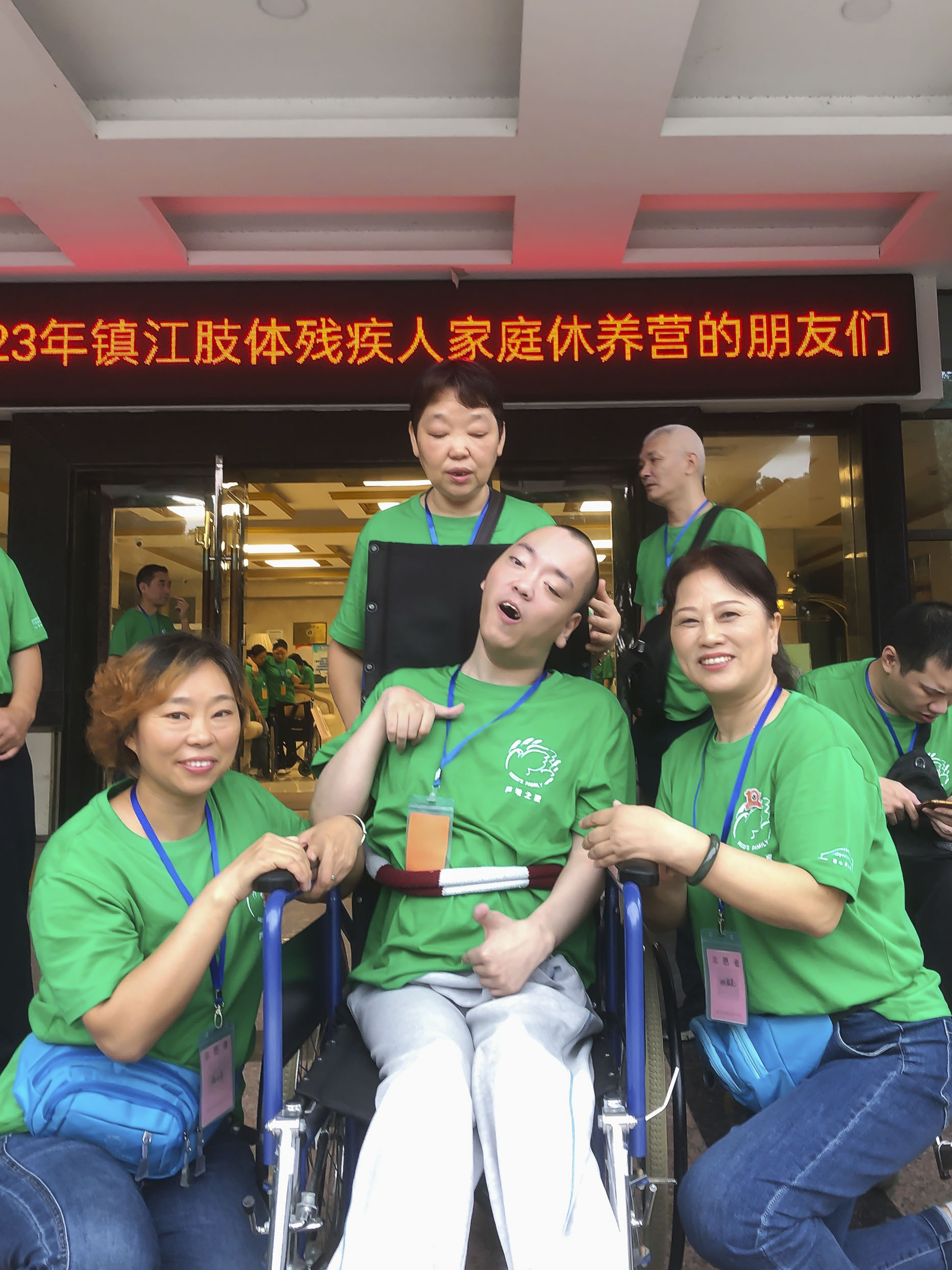 Lu Tong in his new wheelchair, a gift from Joni and Friends, smiling with the three volunteer women at the International Family Retreat.