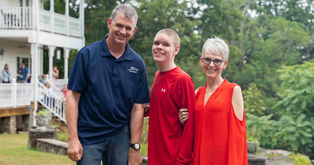 Will, Noah, and JJ smiling brightly and posing for the camera outdoors, enjoying their time at the Family Retreat.