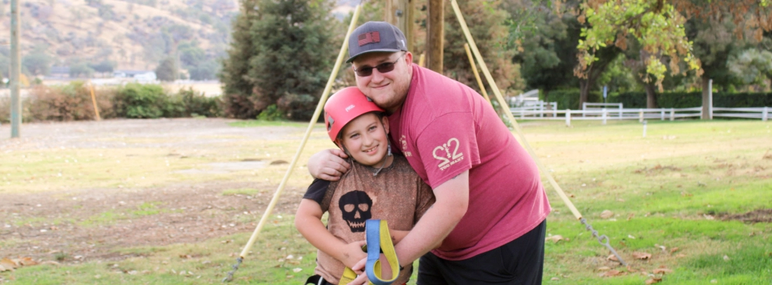 A camper and volunteer at Family Retreat prepare for an outdoor activity