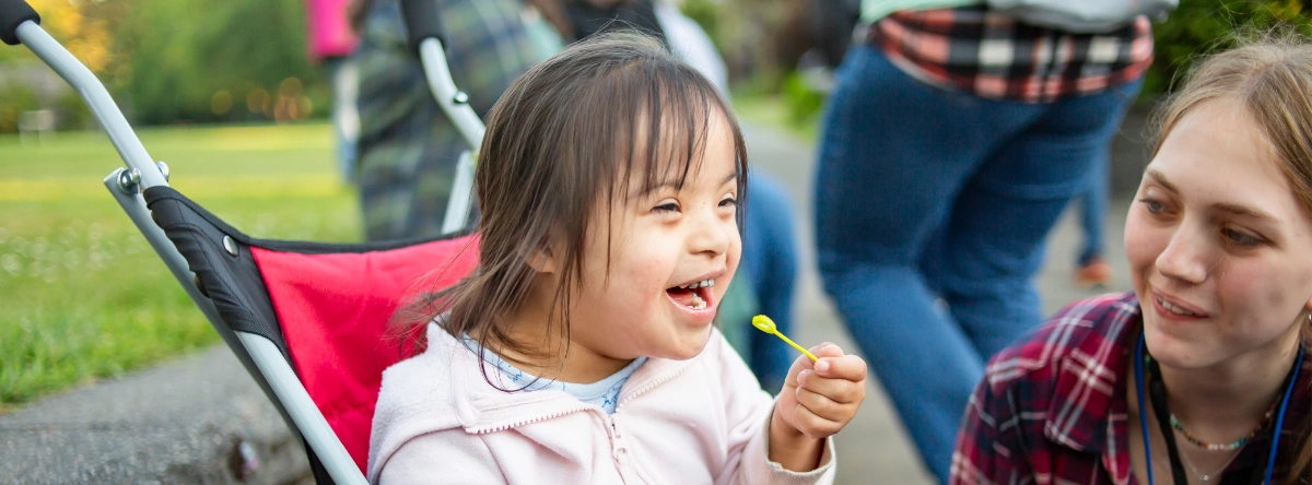 A camper smiles next to a Family Retreat volunteer.