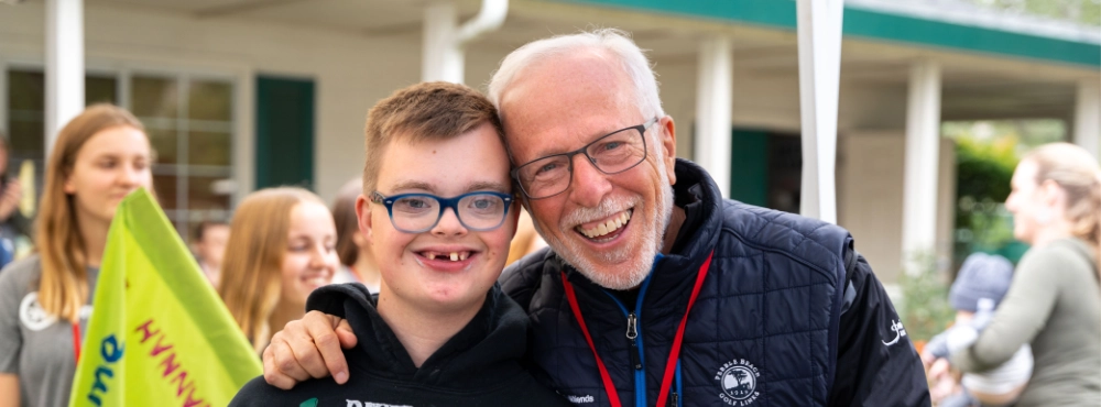 A camper and volunteer pose for a picture at a family retreat