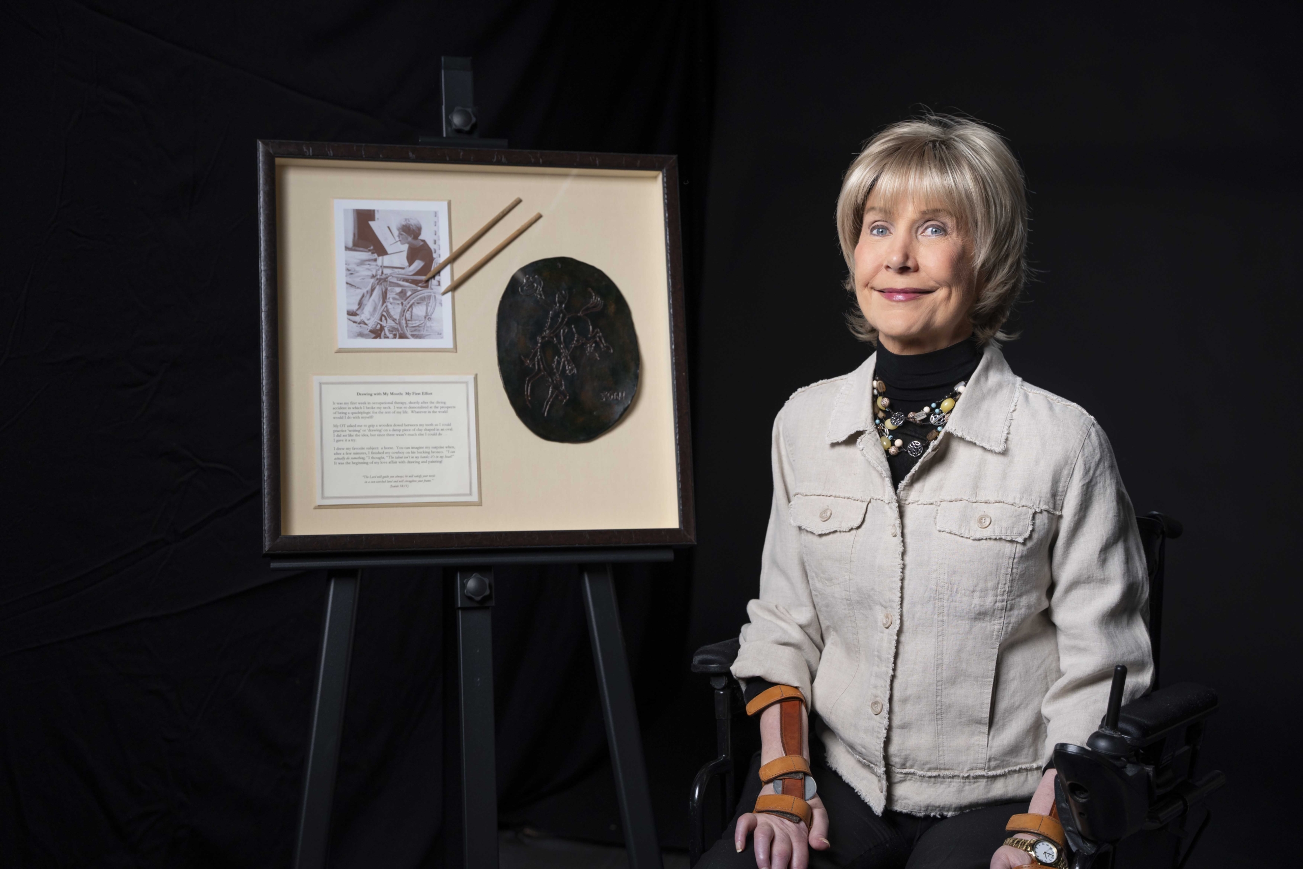 Joni next to her artwork Cowboy on a Bucking Horse. The art is a drawing of a cowboy riding a bucking bronco on a glazed-and-fired ceramic.