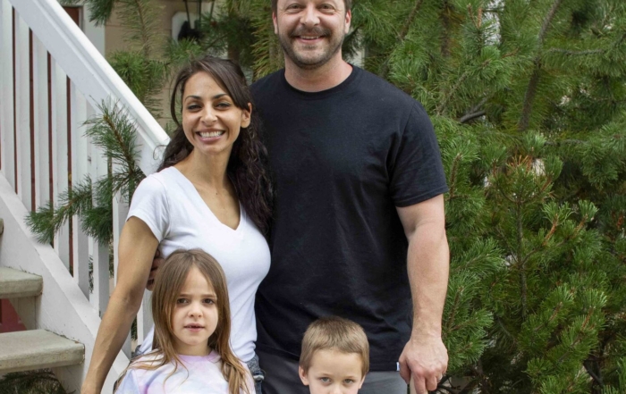 Lea and Gabriel smiling and posing for the camera while standing outdoors with their daughter Isa and son Isaiah.